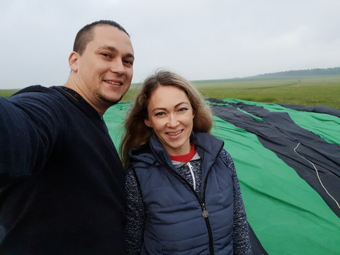 Adventure love couple on hot air balloon watermelon. Man and woman kiss hug love each other. Burner directing flame into envelope. Fly in morning blue sky. Happy people take selfie in hot air ballon.