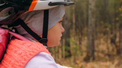 One caucasian children rides bike road in autumn park. Little girl riding black orange cycle in...