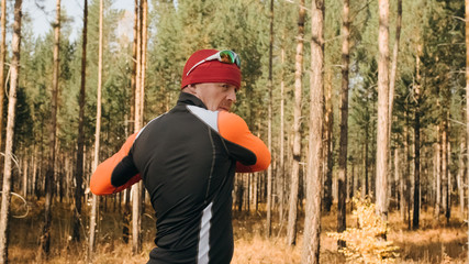 Training an athlete on the roller skaters. Biathlon ride on the roller skis with ski poles, in the helmet. Autumn workout. Roller sport. Adult man riding on skates. The athlete does the workout.