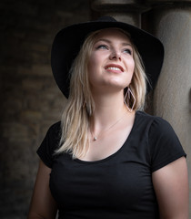 Junge Frau mit Hut blickt verträumt in den Himmel