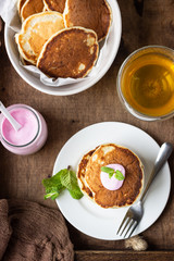 Wooden tray with pancakes, yogurt, herbal tea and mint for perfect breakfast. American cuisine.