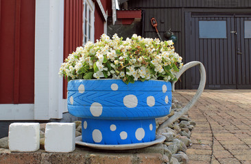 Tasse mit Blumen als Gartenschmuck