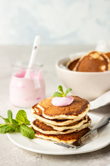 Pancakes with pink yogurt and mint, light grey stone background. Perfect breakfast. 