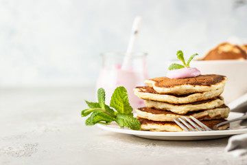 Pancakes with pink yogurt and mint, light grey stone background. Perfect breakfast. 