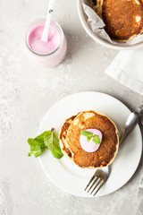 Pancakes with pink yogurt and mint, light grey stone background. Perfect breakfast. 