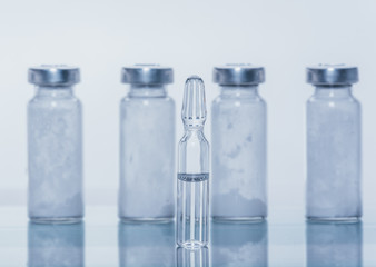 Glass medical ampoule vial for injection. Medicine is liquid sodium chloride with of aqueous solution in ampulla. Close up. Bottles ampule multicolor on background color and water. Human plasma.