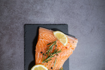 Slate plate with salmon fillet with lemon and herbs. Copy space.