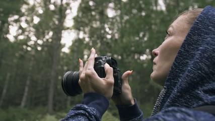 Traveler photographing scenic view in forest. One caucasian woman shooting close up look. Girl take photo video on dslr mirrorless camera. Professional photographer travel with backpack. Outdoor.