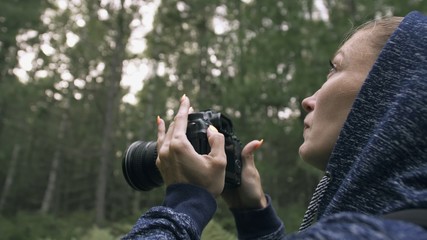 Fototapeta premium Traveler photographing scenic view in forest. One caucasian woman shooting close up look. Girl take photo video on dslr mirrorless camera. Professional photographer travel with backpack. Outdoor.