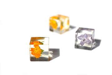 Dried flowers in epoxy resin cubes isolated on white background. Handmade jewelry.