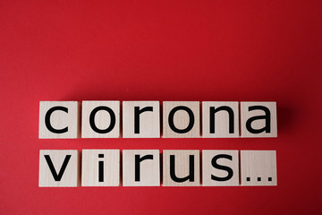 Coronavirus word written on wood block, which are located on a red background.