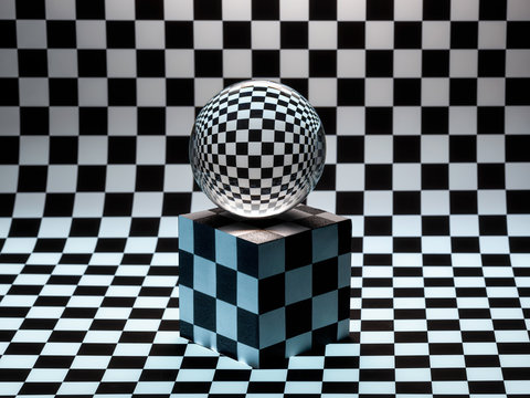 Glass sphere on a cube on a checked background