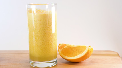 glass of orange juice and oranges on wooden table