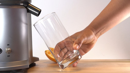 woman holding glass waiting for juicer to dispense juice