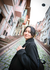 Girl in black turns  back and looks to camera while walking away in a scenic place.