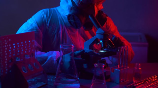 Scientist in scientific laboratory looking into microscope, research and test medical bio material. Researcher working on developement a new nano technology. Science and technology engineering.
