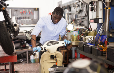 Confident man worker repairing motorcycle in workshop