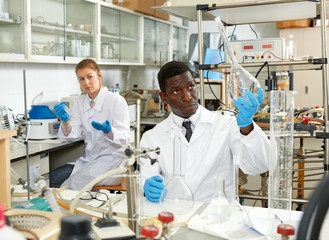 Male lab technicians with different glass tubes, girl on background