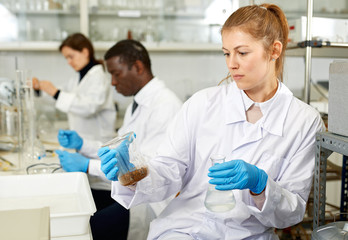 Serious woman lab  scientist in glasses working with reagents and test tubes