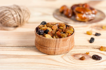 Golden raisins in a bowl on a light wooden background. Dried fruits.