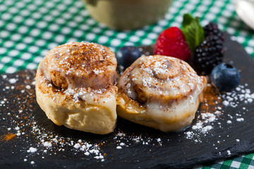 Tasty  cinnamon rolls with fresh berries and powdered sugar  at plate