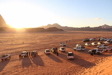 Pickup trucks stands in Wadi Rum desert in Jordan during beautiful sunset and waits for tourists....