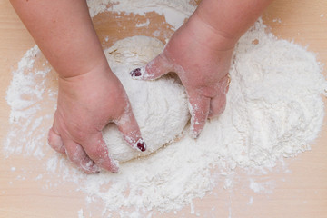 Kneading dough with flour on a wooden table at home
