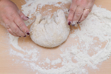 Kneading dough with flour on a wooden table at home