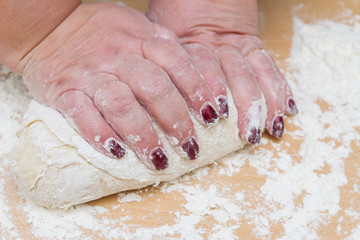 Kneading dough with flour on a wooden table at home