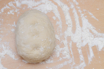 Prepared kneaded dough on a wooden table at home