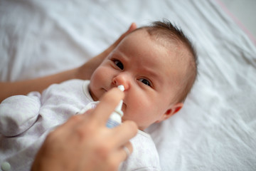 Woman using nasal spray for baby