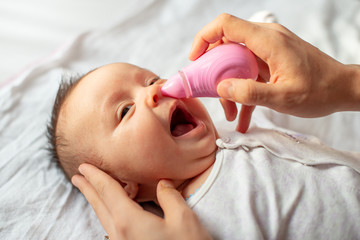 mother using baby nasal aspirator mucus nose suction