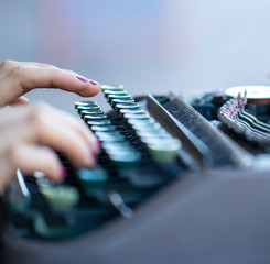 A closeup of a woman's hands typing on a typewriter