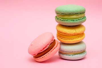 Fresh vibrant colored macarons, or macaroons on a pink background with copy space