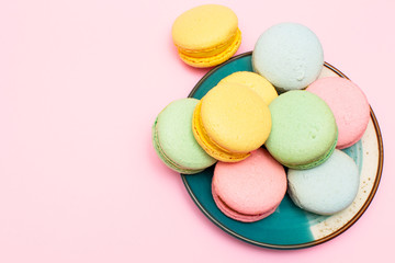 Fresh vibrant colored Macarons, or macaroons on a plate, on a pink background with copy space
