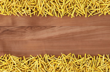 Fried potato chips arranged in stripes on wood background. Top view of french fries. Flat lay fast food concept.