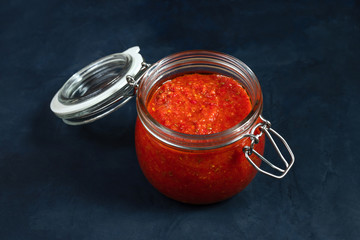Hot chili pepper sauce paste harissa. Adjika. Traditional Tunisia, Georgian and Arabic cuisine. Homemade rose harissa in a glass jar.