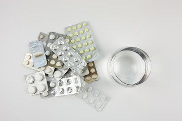 Different pills with glass of water