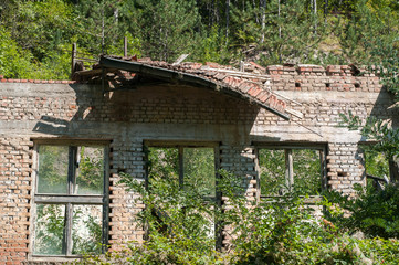 Fototapeta na wymiar Old obsolete industrial building facade with broken windows