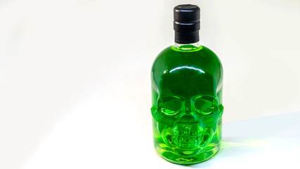 A skull bottle with a liquid, alcohol drink. Colored watery drink. Isolated on white background.