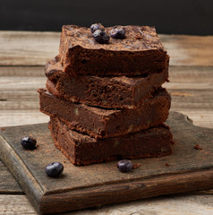 stack of square baked slices of brownie chocolate cake with walnuts