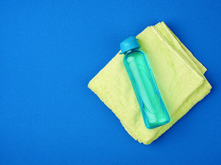 folded green terry towel and a transparent bottle of water on a blue background
