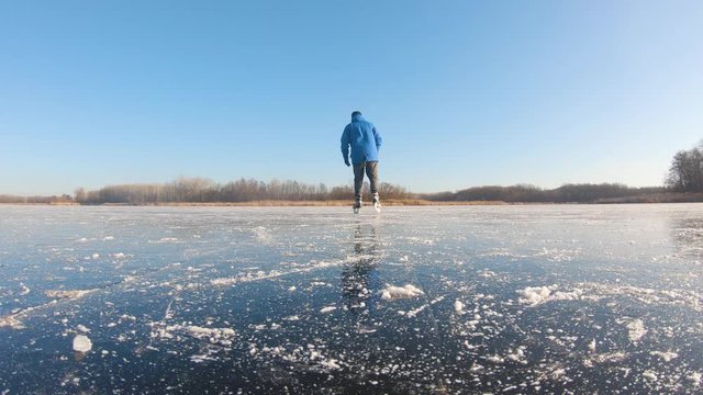 Man skating on ice on lake in winter sunny day.