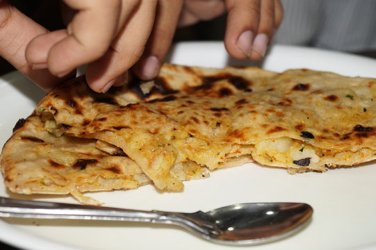 Cropped Image Of Person Eating Paratha In Plate