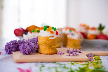 Easter cake. Traditional mini muffin with easter decoration on a wooden board. Easter eggs and flowers of lilac