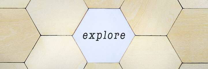 Wooden hexagon missing from puzzle, revealing the word explore in a conceptual image of exploring and discovery