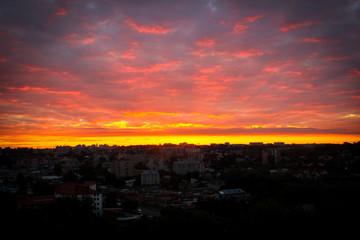 View of the city at sunrise. Beautiful pink sky covered with clouds.