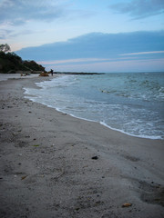 The soft sea waves gently roll on the sandy beach. Beautiful picture of dawn on the seashore.