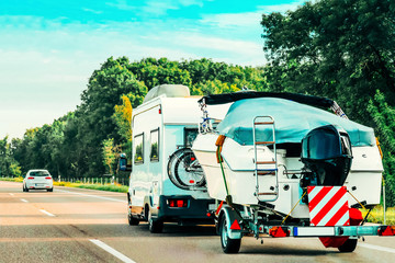 RV Camper Car with motor boat on Road. Caravan and motorhome in trip in Switzerland.