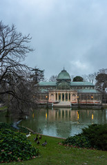 Fototapeta premium Vertical image of sunrise in the Retiro Park in Madrid, next to the glass palace on a cloudy day, travel concept